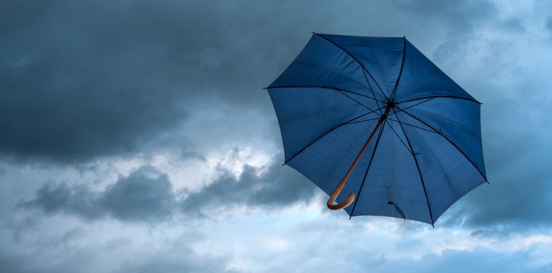 Bewölkter Himmel mit schwebendem Regenschirm als Symbol für die richtige Vorsorgelösung, die wie ein Regenschirm vor "schlechtem Wetter" im Alter schützt